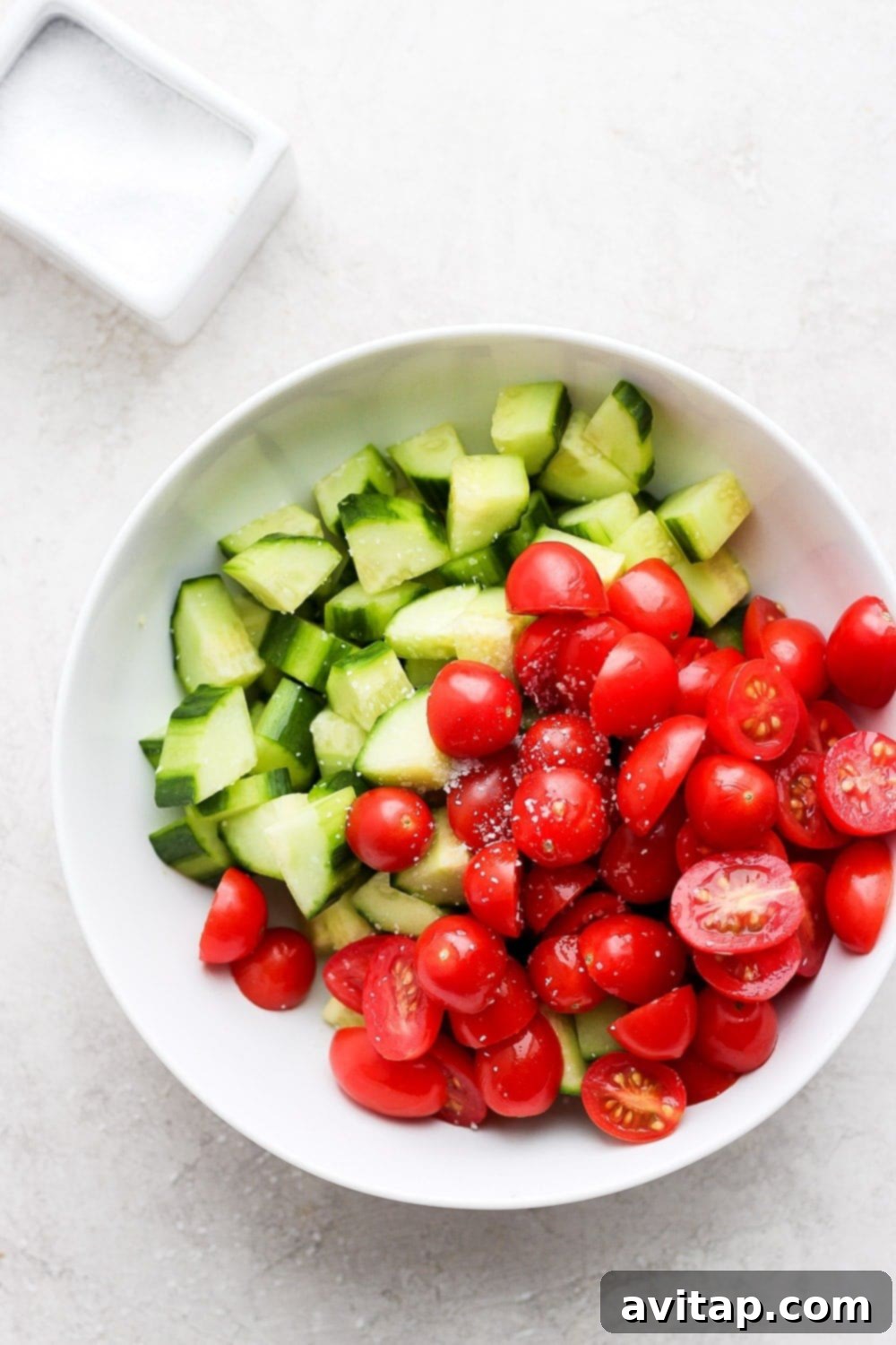 Close-up of fresh, colorful cucumbers and cherry tomatoes, perfectly halved and sliced, ready for Greek salad preparation