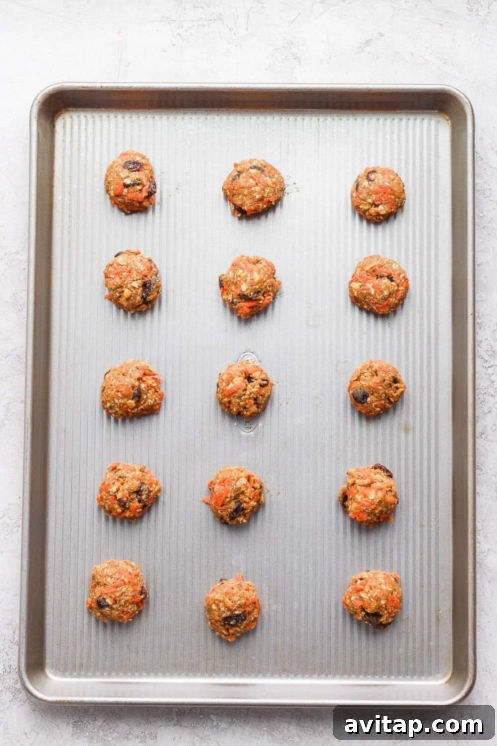 Pre-Bake Perfection: Cookie Dough Balls on a Sheet Freshly rolled cookie dough balls neatly arranged on a baking sheet, ready to be baked into delicious oatmeal carrot cake cookies.