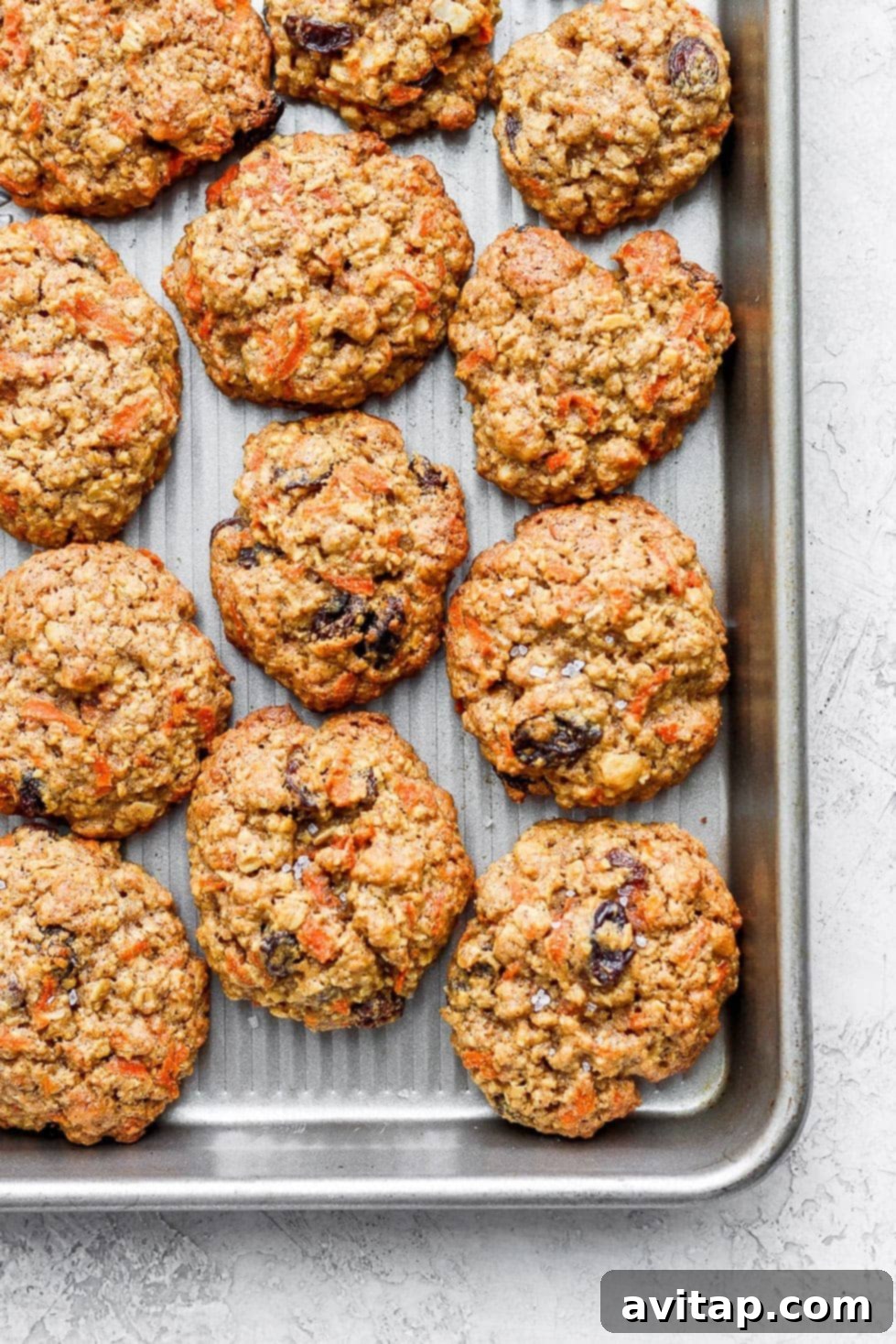 Freshly Baked Oatmeal Carrot Cake Cookies on Cooling Rack A close-up shot of several perfectly baked oatmeal carrot cake cookies stacked on a wire cooling rack, showing off their golden-brown edges and inviting texture.