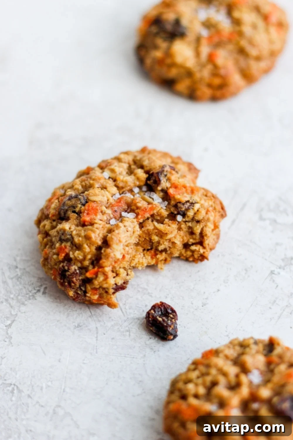 Irresistible Oatmeal Carrot Cake Cookie: A Closer Look at the Texture A delicious oatmeal carrot cake cookie with a bite taken out, revealing its moist interior packed with oats, carrots, and raisins, perfectly highlighting its inviting texture.