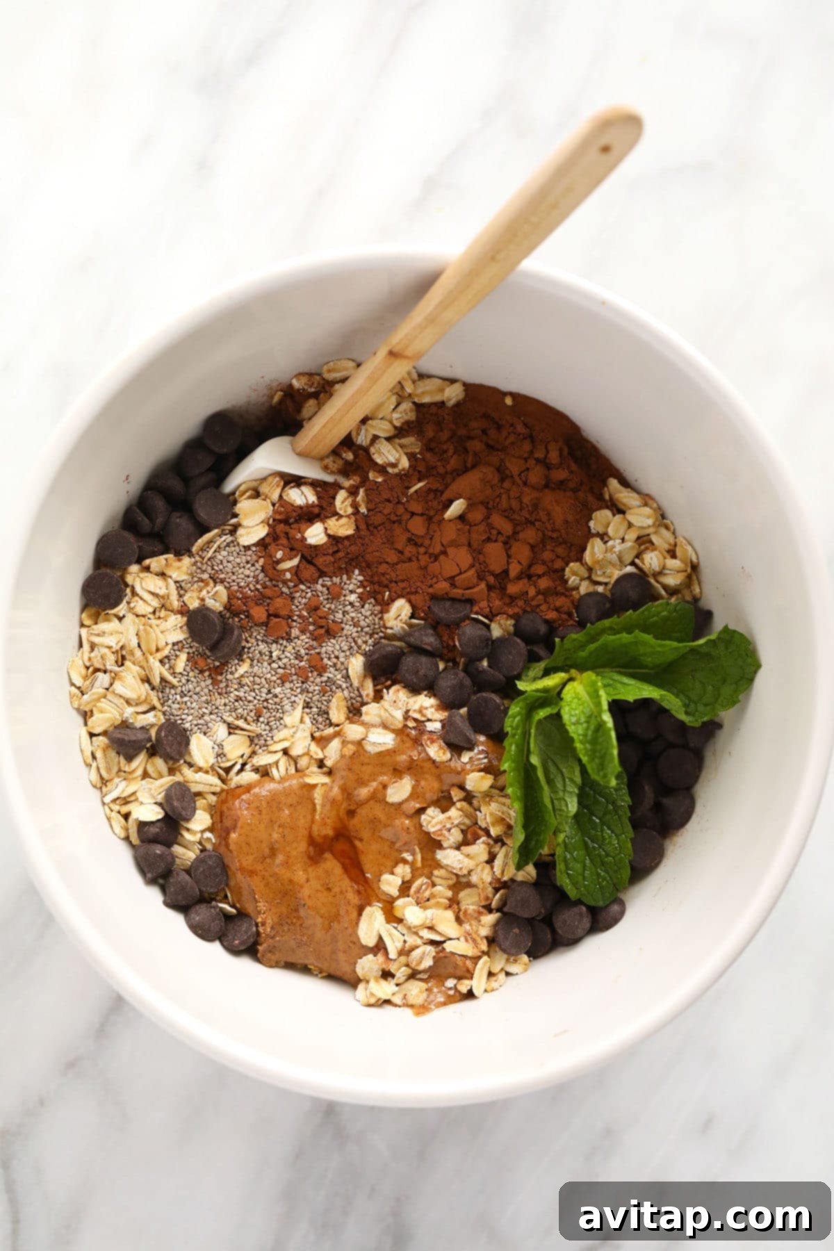 Key Ingredients for Mint Chip Overnight Oats A vibrant array of fresh ingredients laid out on a clean surface, including rolled oats, rich cocoa powder, tiny chia seeds, creamy almond butter, a jug of almond milk, and a bottle of peppermint extract, ready for making delicious overnight oats.