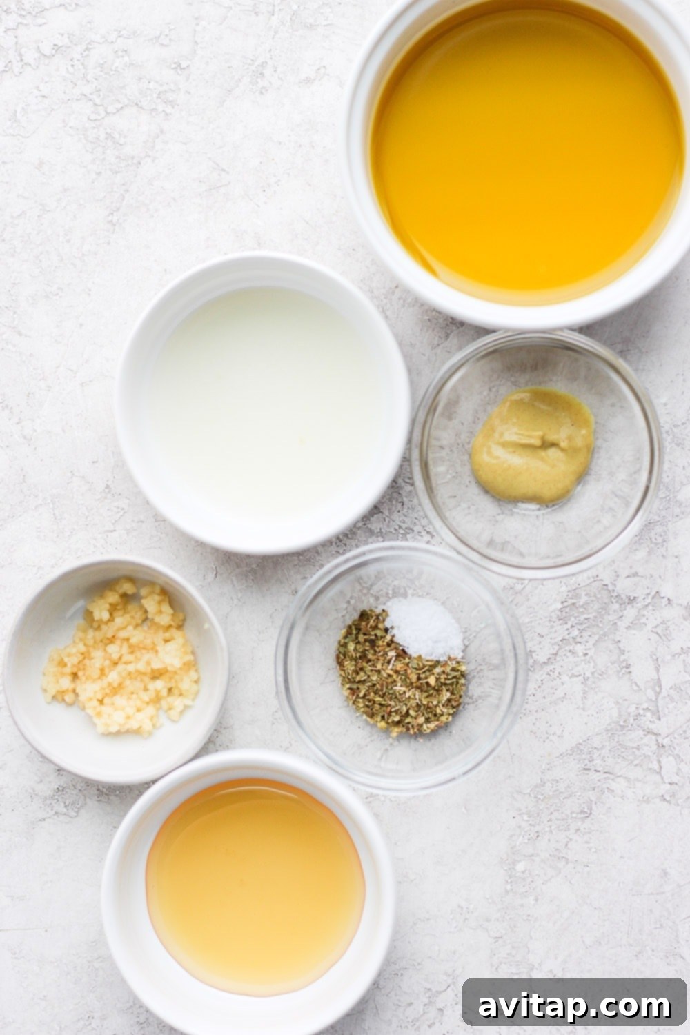 Individual ingredients for the Greek salad dressing recipe laid out on a table