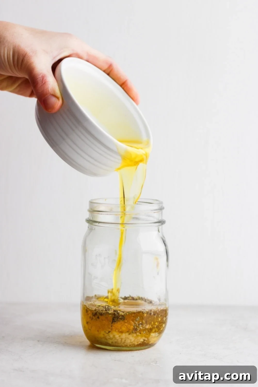 Pouring olive oil into a mason jar for Greek dressing