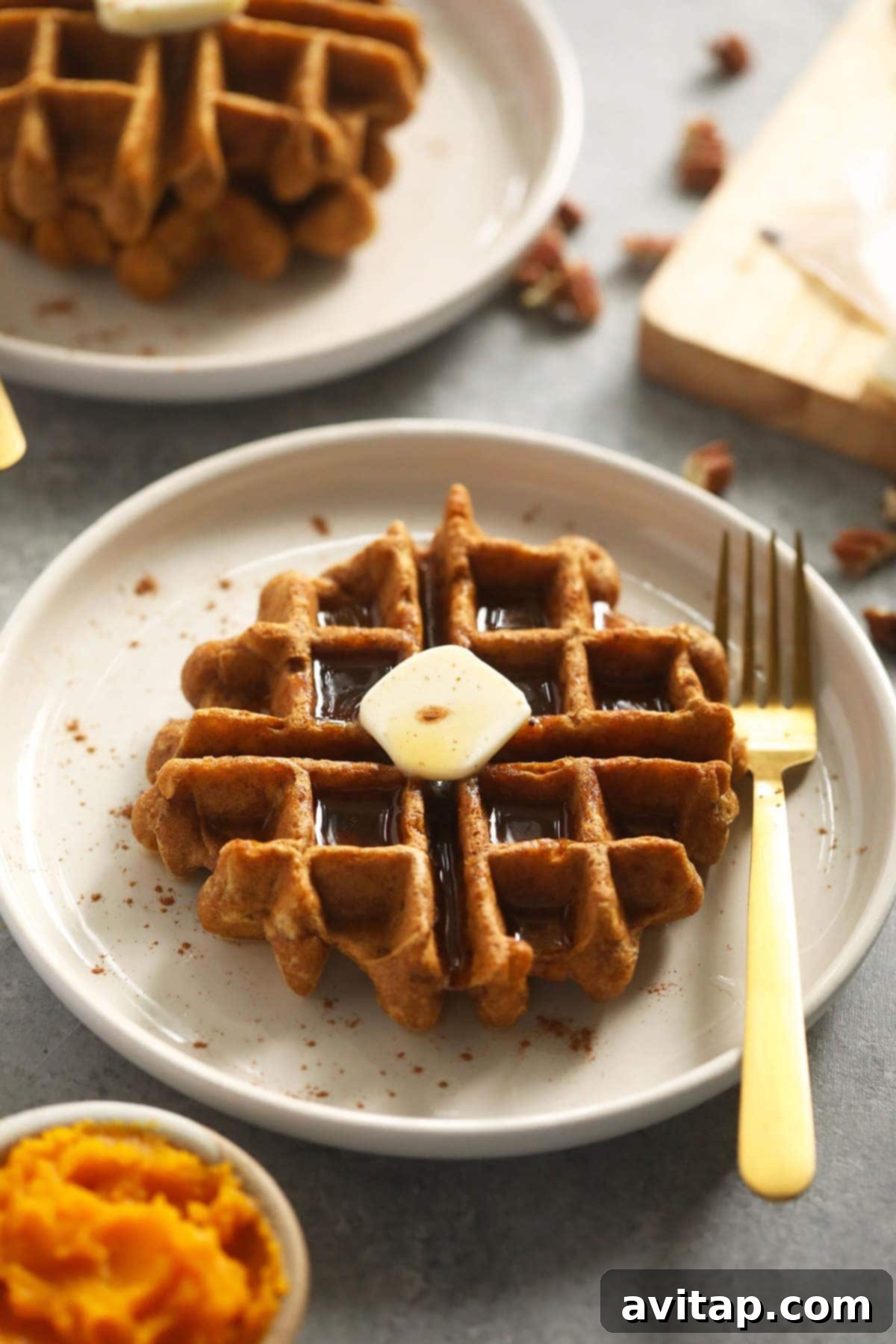 Golden brown gluten-free pumpkin waffle on a white plate, ready to be served.