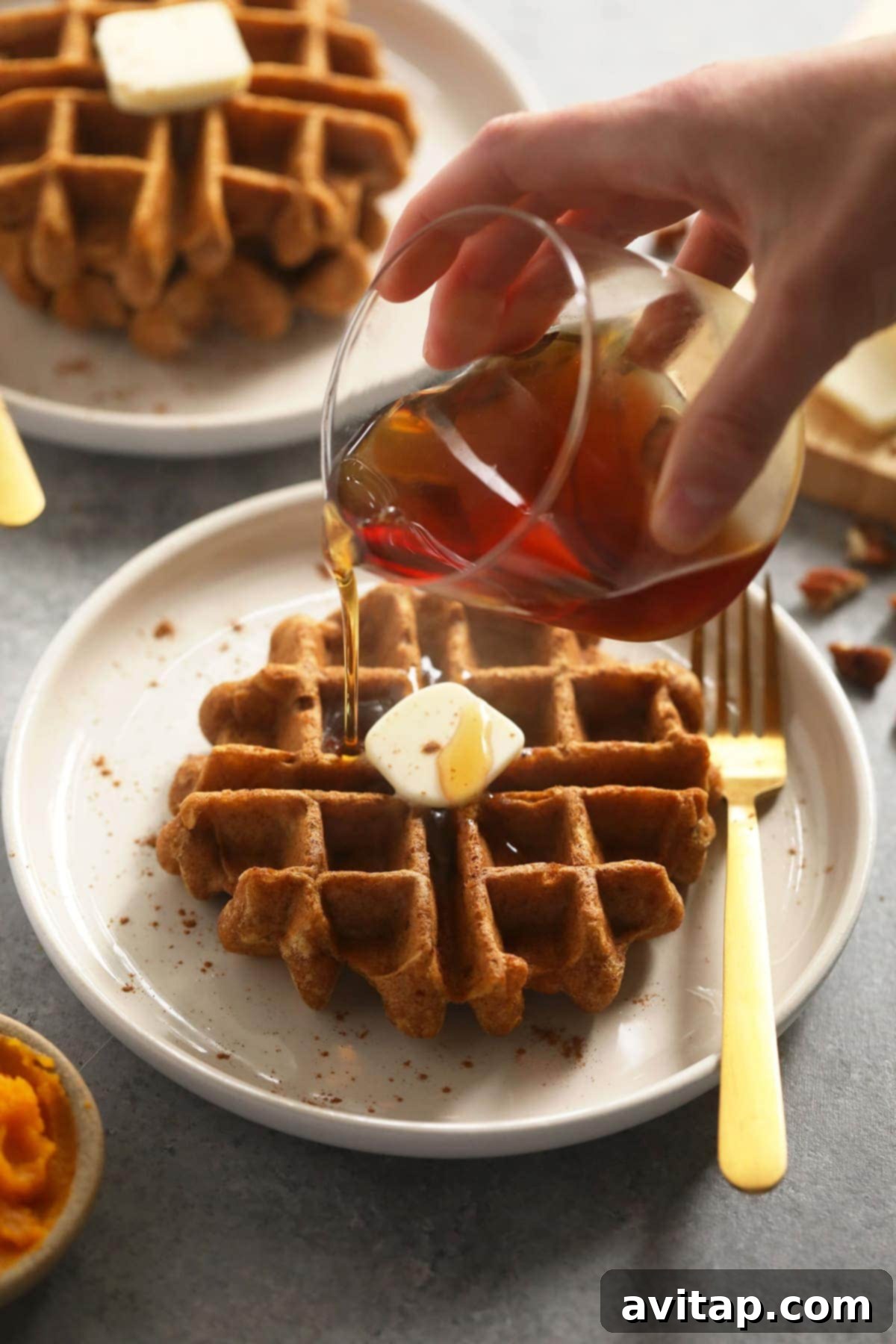 Close-up of fluffy gluten-free pumpkin waffles stacked with syrup.