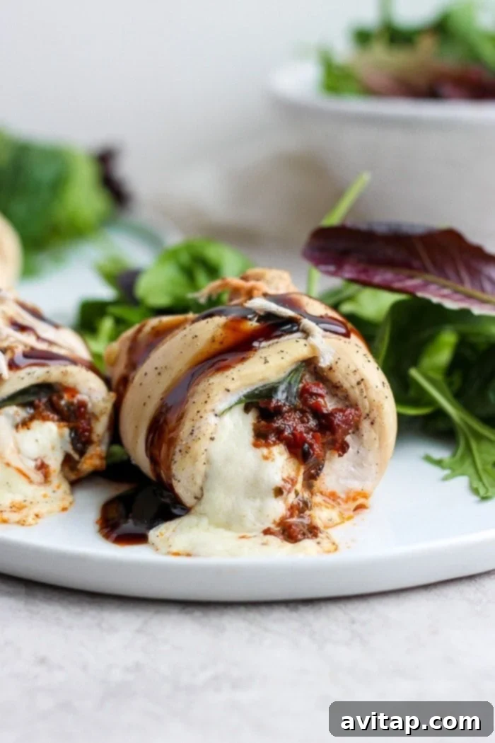 Golden-baked Caprese stuffed chicken breast on a white plate, garnished with fresh basil and a balsamic glaze drizzle.