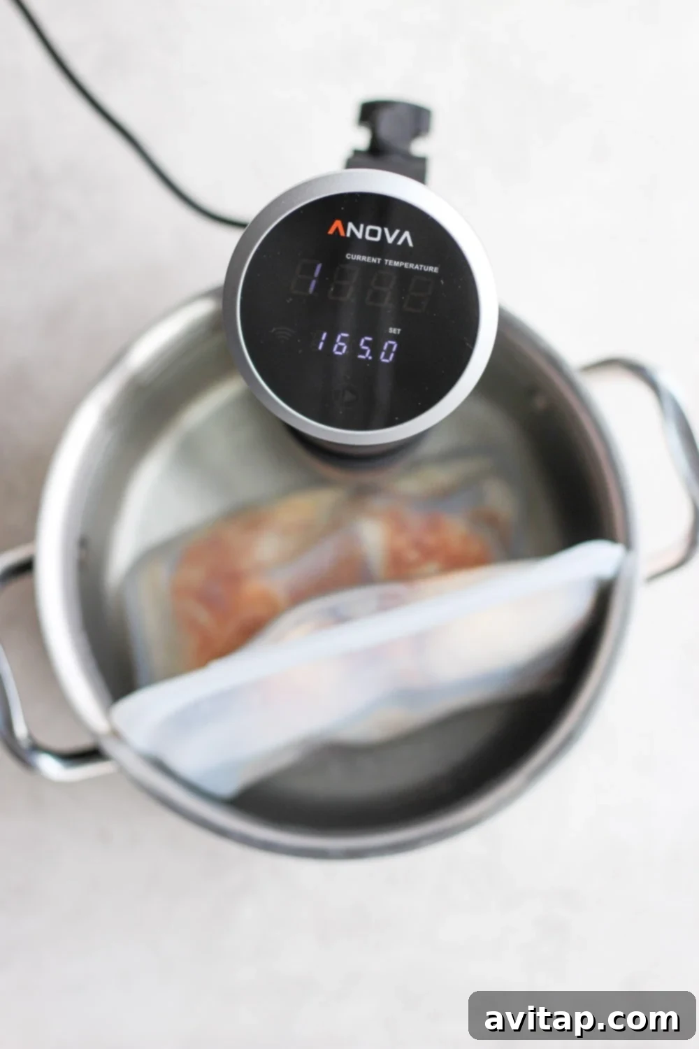 Sous vide immersion circulator set to 165 degrees Fahrenheit in a water bath