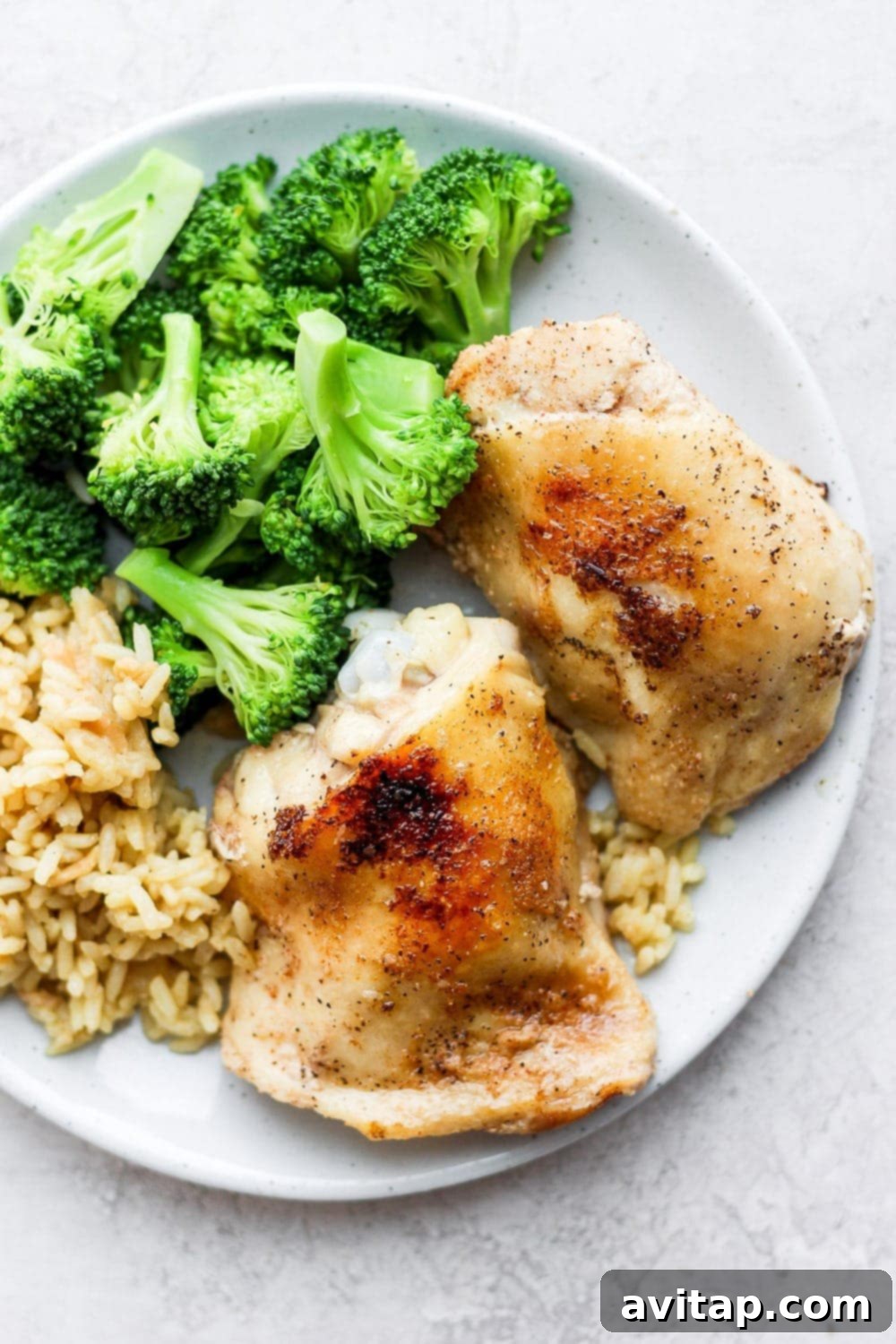 Crispy sous vide chicken thighs served on a plate with brown rice and steamed broccoli