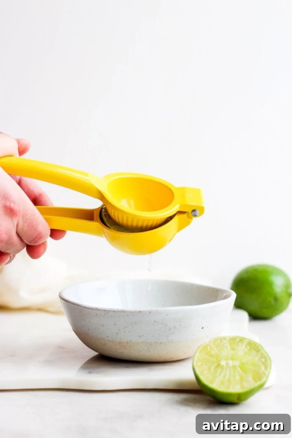 Close-up of hands expertly juicing fresh limes, essential for the best skinny margarita.
