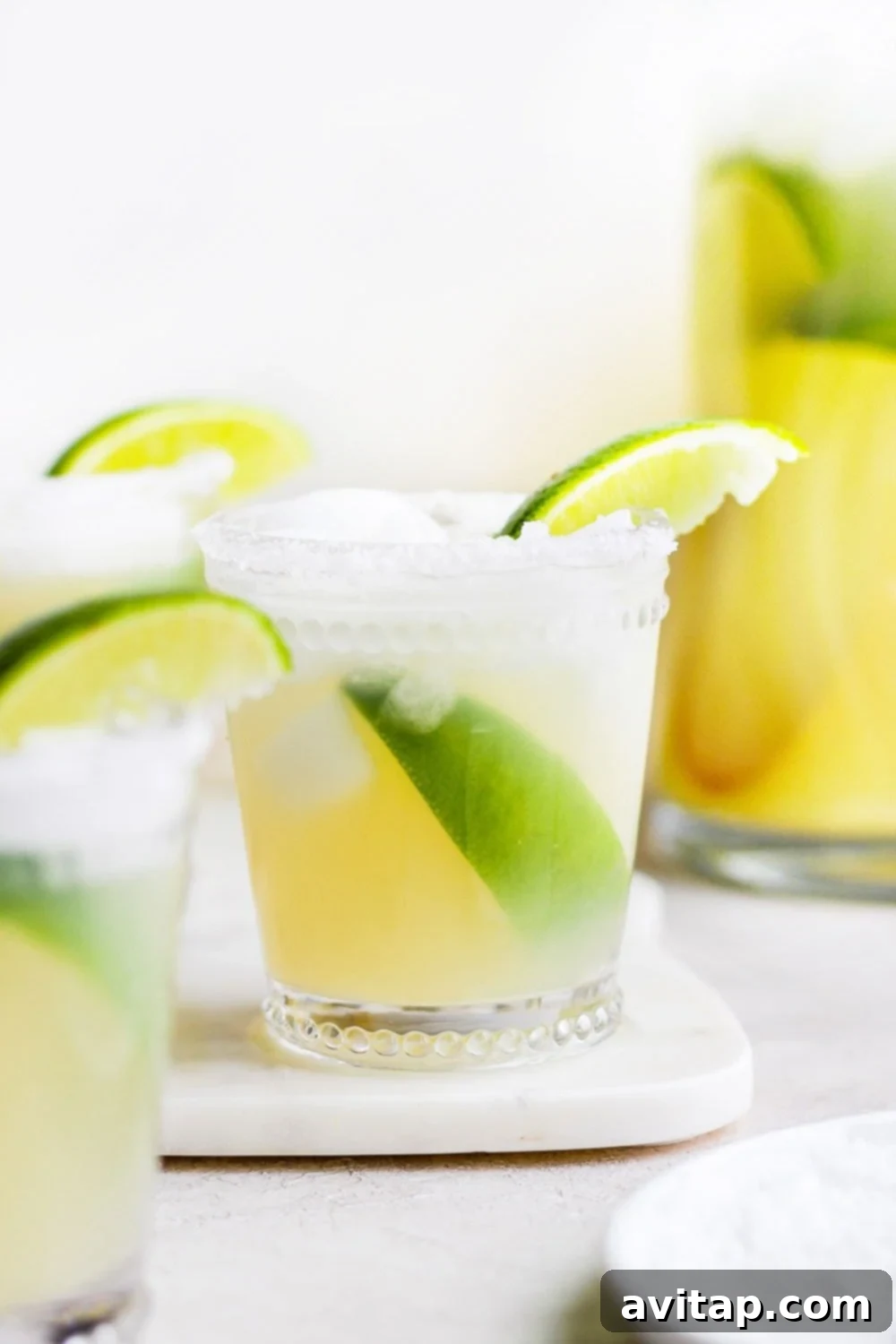 Two glasses of skinny margarita, beautifully garnished with lime slices, against a light background.