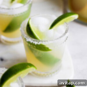 Two skinny margaritas garnished with lime wedges on a white plate.