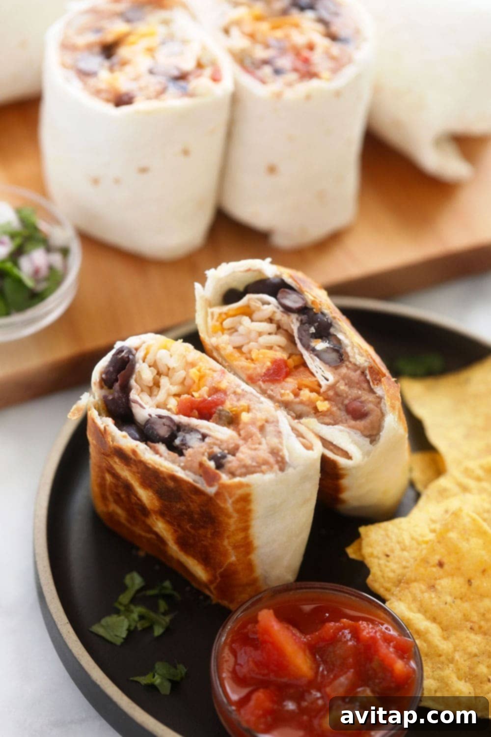 Simple 6-Ingredient Bean Burritos 2 Delicious make-ahead bean and cheese burrito served on a plate with tortilla chips, ready to eat.