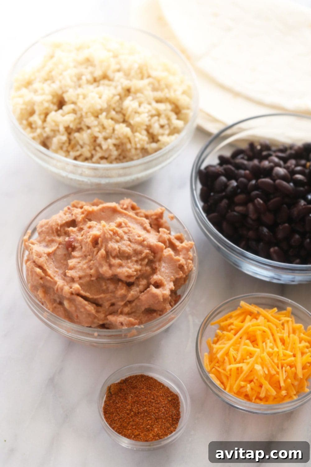 Simple 6-Ingredient Bean Burritos 3 Six simple ingredients laid out for making make-ahead bean burritos: tortillas, rice, refried beans, black beans, cheese, and salsa.