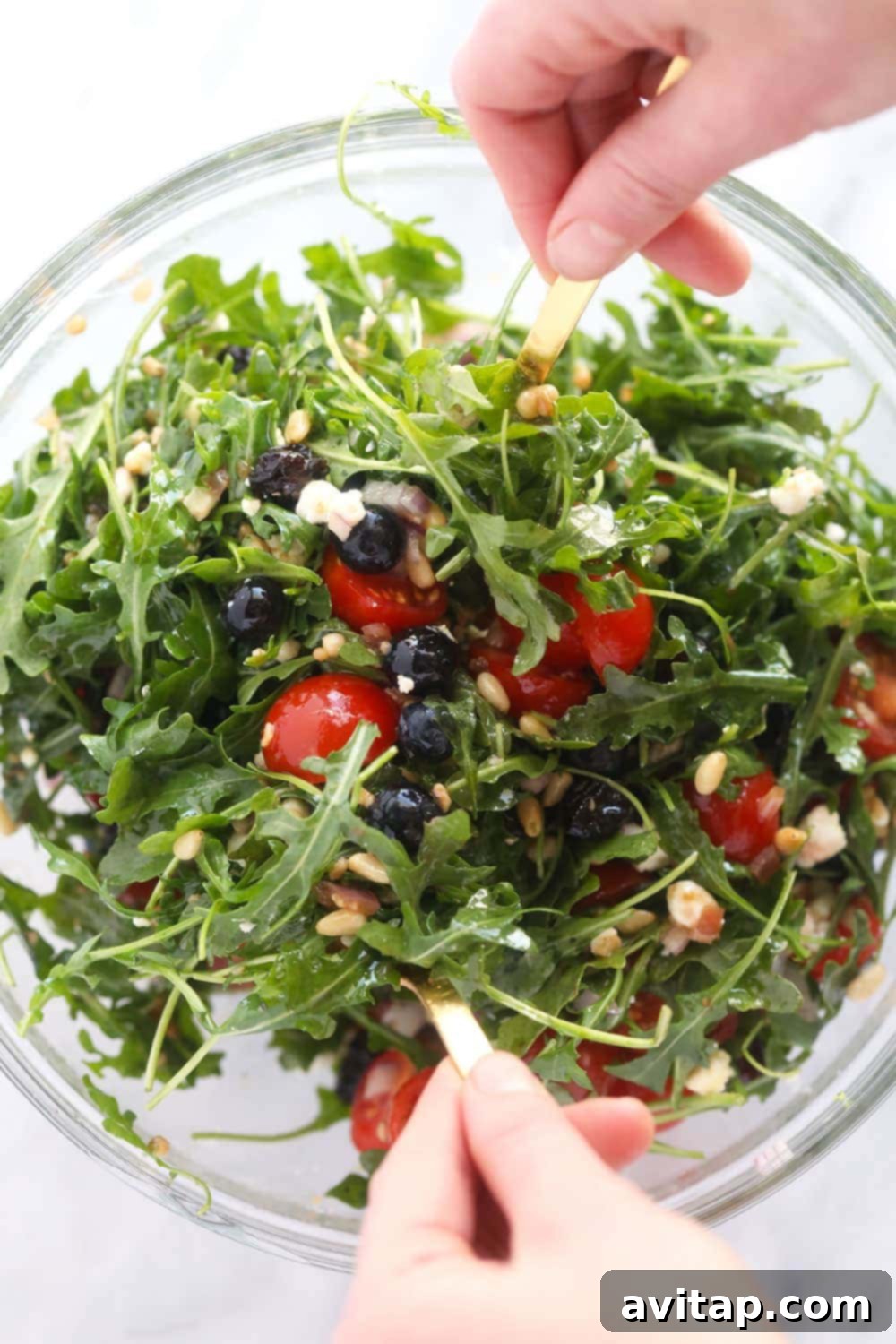 A large mixing bowl filled with fresh arugula salad, featuring a colorful blend of ingredients.