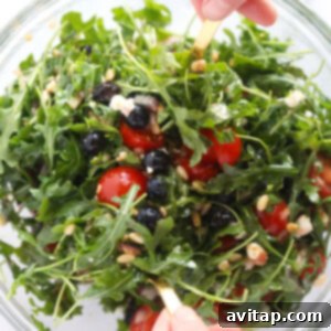 Arugula salad with all ingredients in a mixing bowl before dressing.
