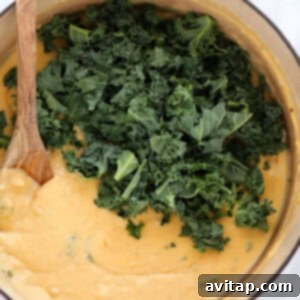 A pan with kale and a wooden spoon.