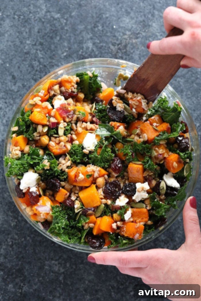 A large bowl of Farro Salad being gently stirred to combine all the vibrant ingredients.