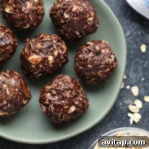 Cocoa oat balls decorated with peanut butter, placed on a plate alongside a bowl of oats.