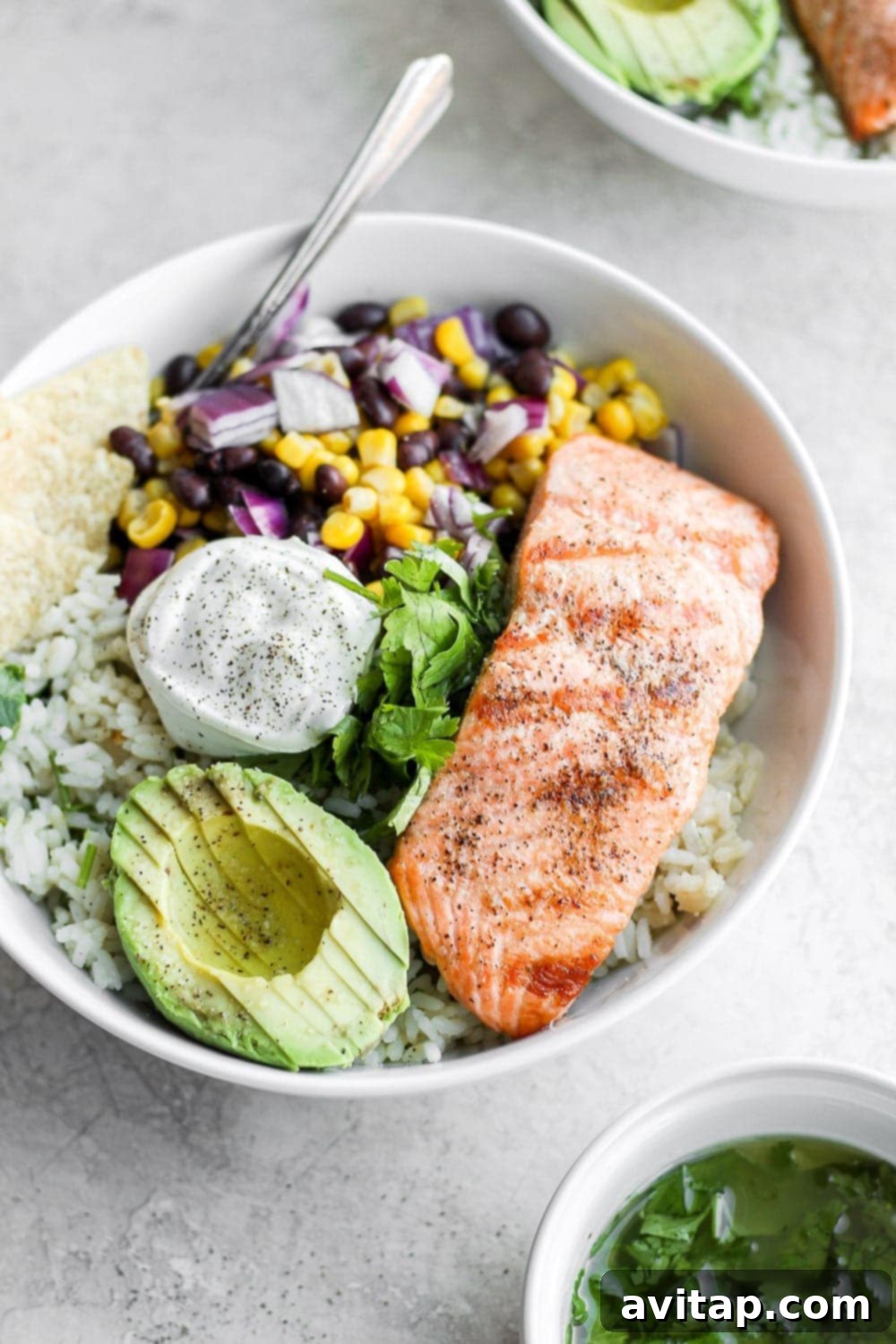 Zesty Salmon Power Bowls 5 completed fiesta salmon rice bowl with a dollop of sour cream and tortilla chips