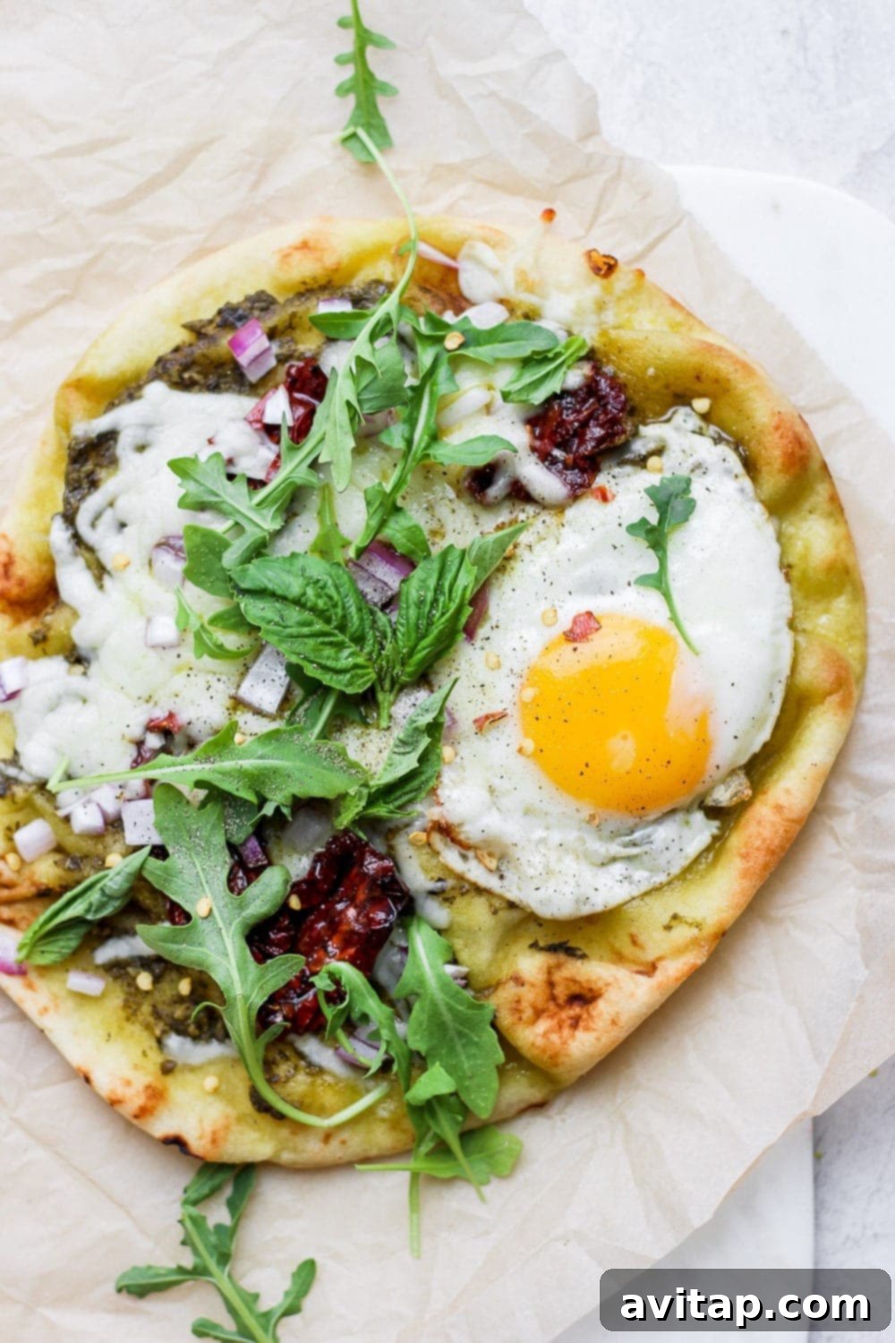Morning Naan Pizza 2 A delectable Naan Breakfast Pizza, topped with a perfectly fried egg, fresh greens, and savory ingredients, served on a rustic plate.