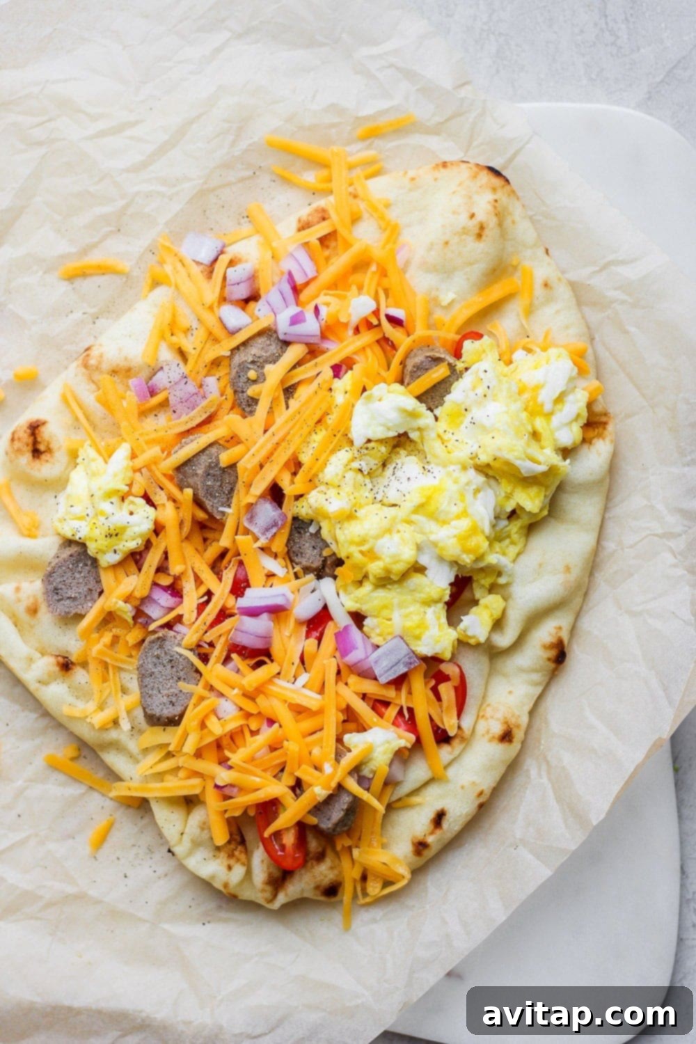 Morning Naan Pizza 6 A vibrant Naan pizza generously topped with fluffy scrambled eggs, melted cheese, savory sausage, and fresh red onions.