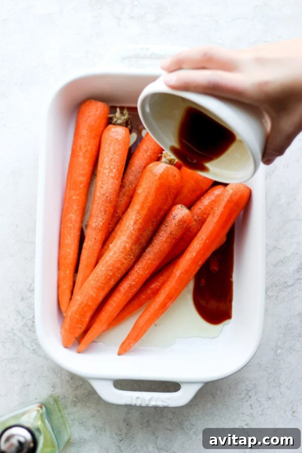 Pouring the savory marinade over the carrots in a dish
