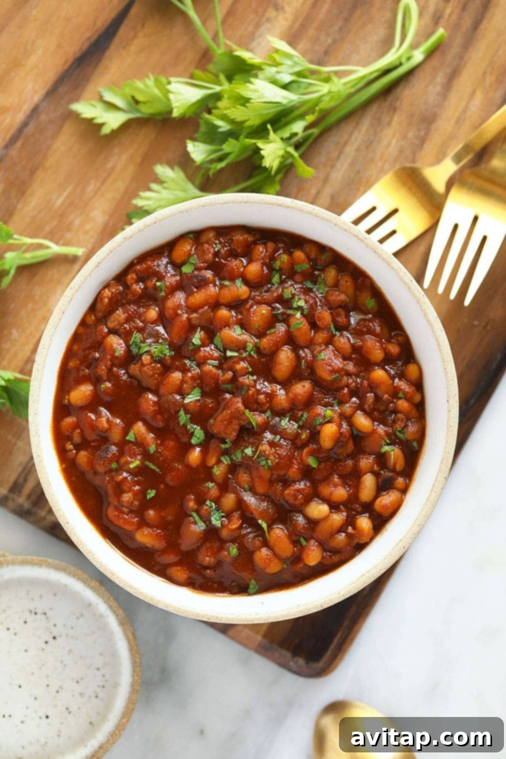 Flavorful BBQ Baked Beans, ready in under an hour with the Instant Pot. Instant Pot Baked Beans in a bowl topped with fresh parsley, ready to be served at a BBQ.