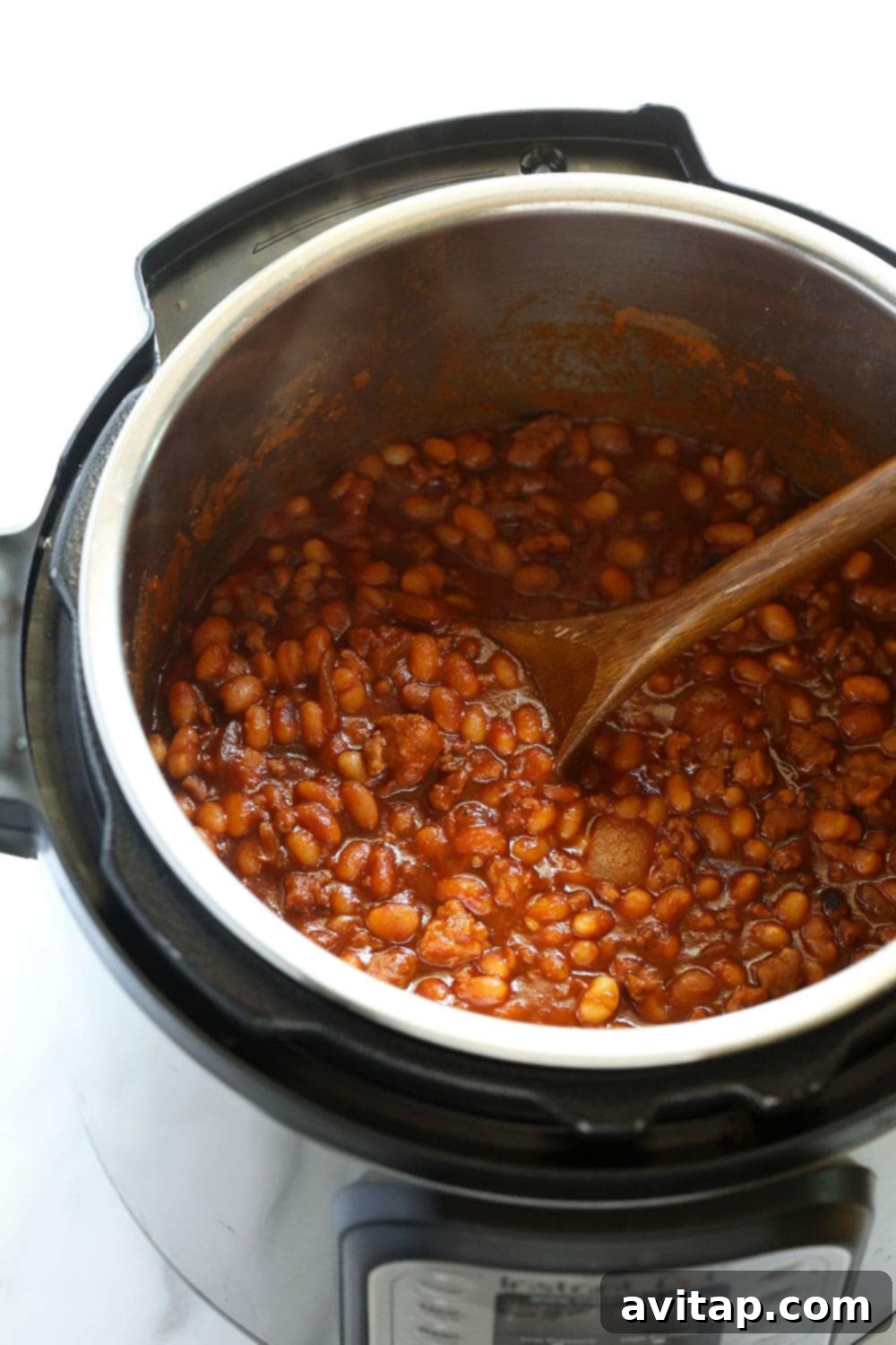 Easy Instant Pot Baked Beans 2 A wooden spoon stirring freshly cooked Instant Pot baked beans, showcasing their rich texture.