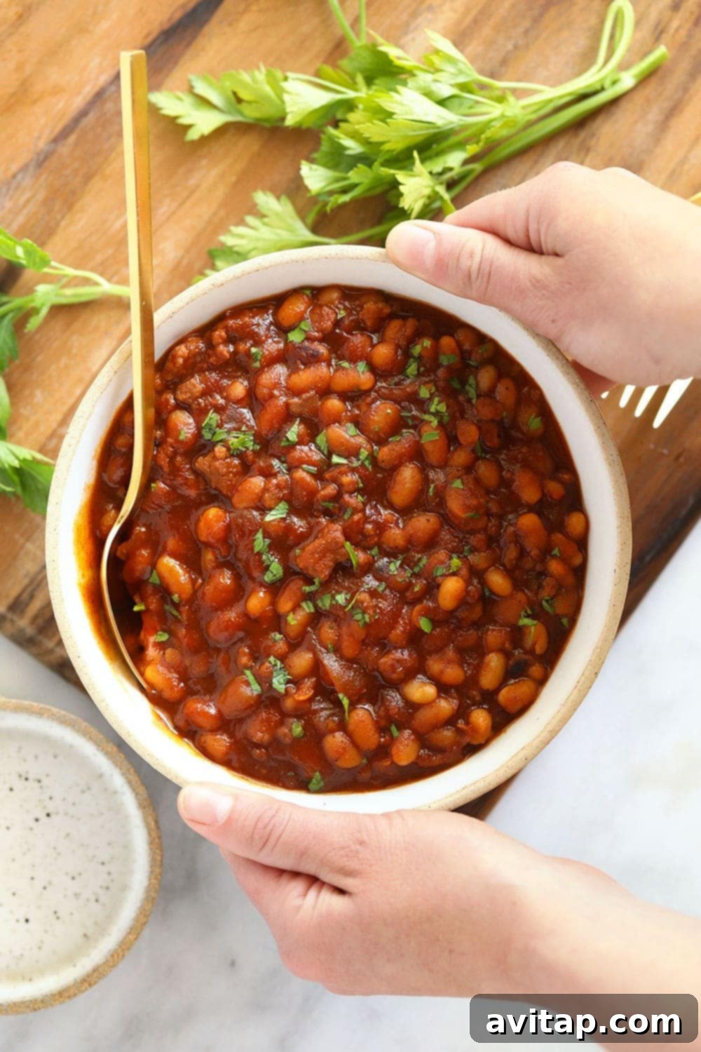 Serve these delicious BBQ baked beans with your favorite summer sides for a family-loved dish. A close-up bowl of rich, smoky BBQ baked beans, garnished lightly.