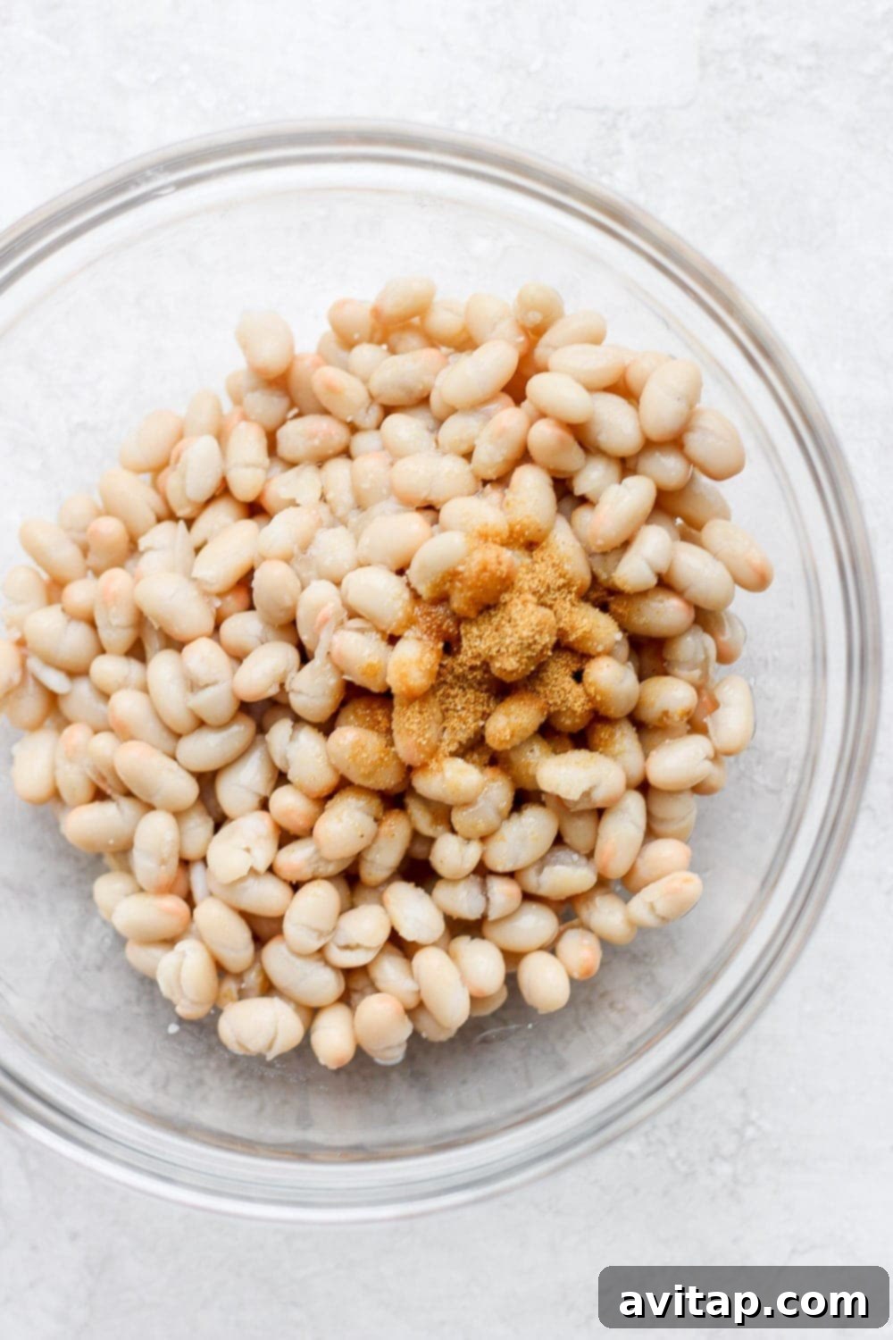 White navy beans mixed with olive oil and spices in a bowl, a key ingredient for a healthy shrimp salad