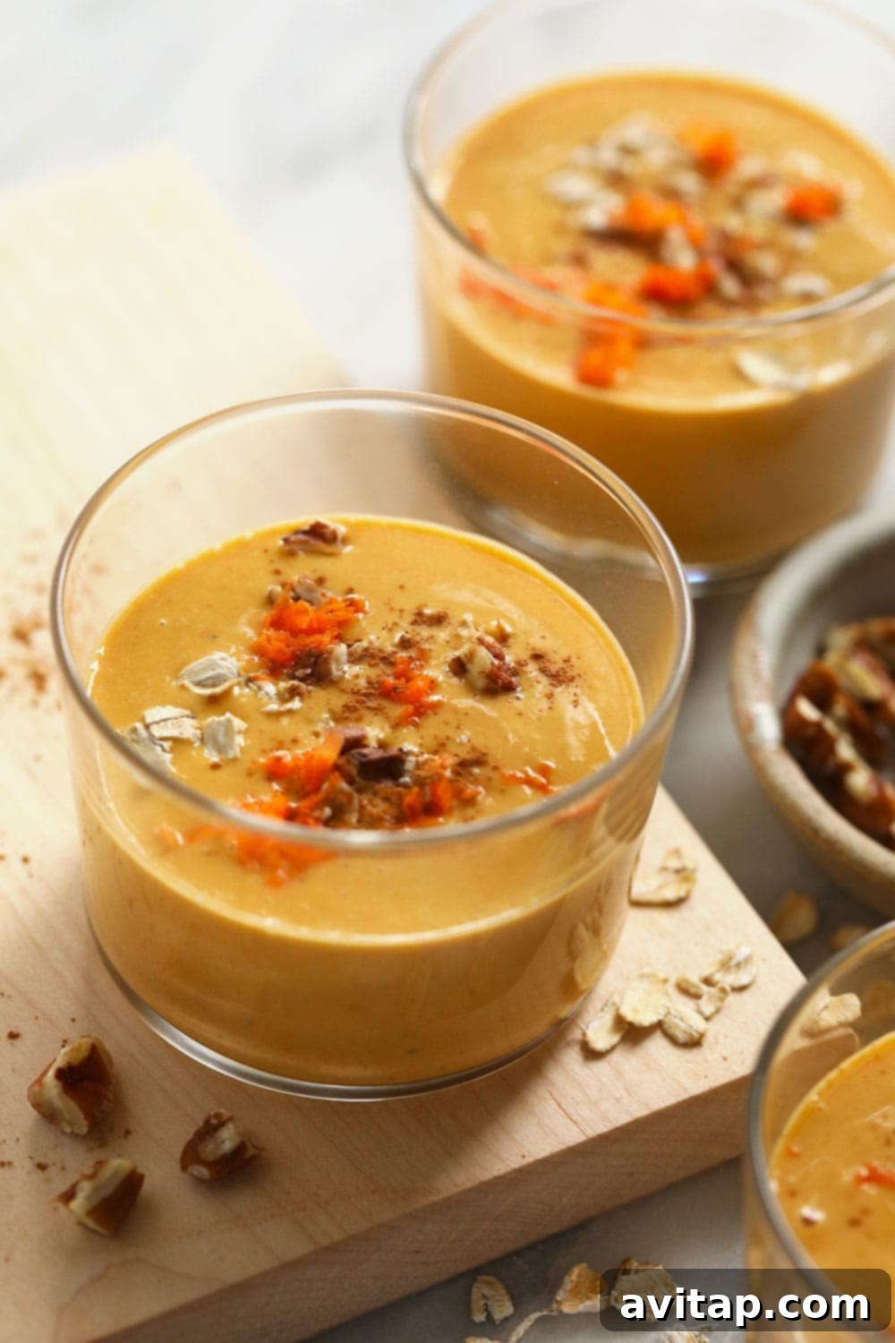 Two glasses filled with creamy carrot cake smoothies, garnished for a delightful presentation.