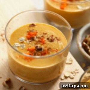A bowl of carrot cake smoothie with oats on a wooden cutting board, ready to be enjoyed.