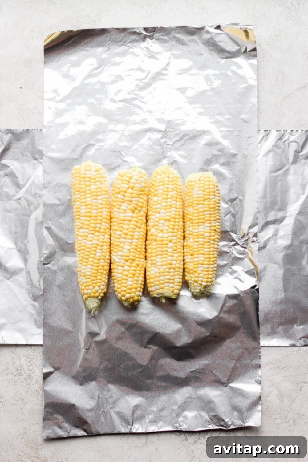 tin foil laid out with 4 ears of corn on it