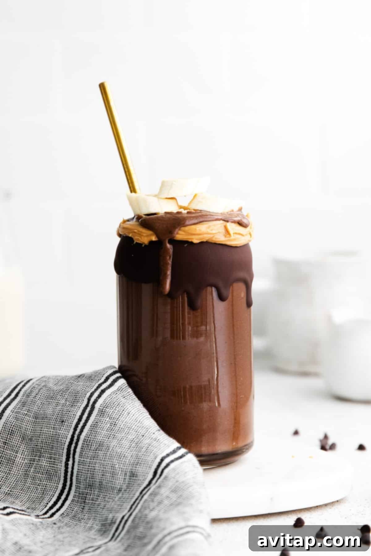 A delicious and healthy chocolate peanut butter banana smoothie with a straw, ready to drink.