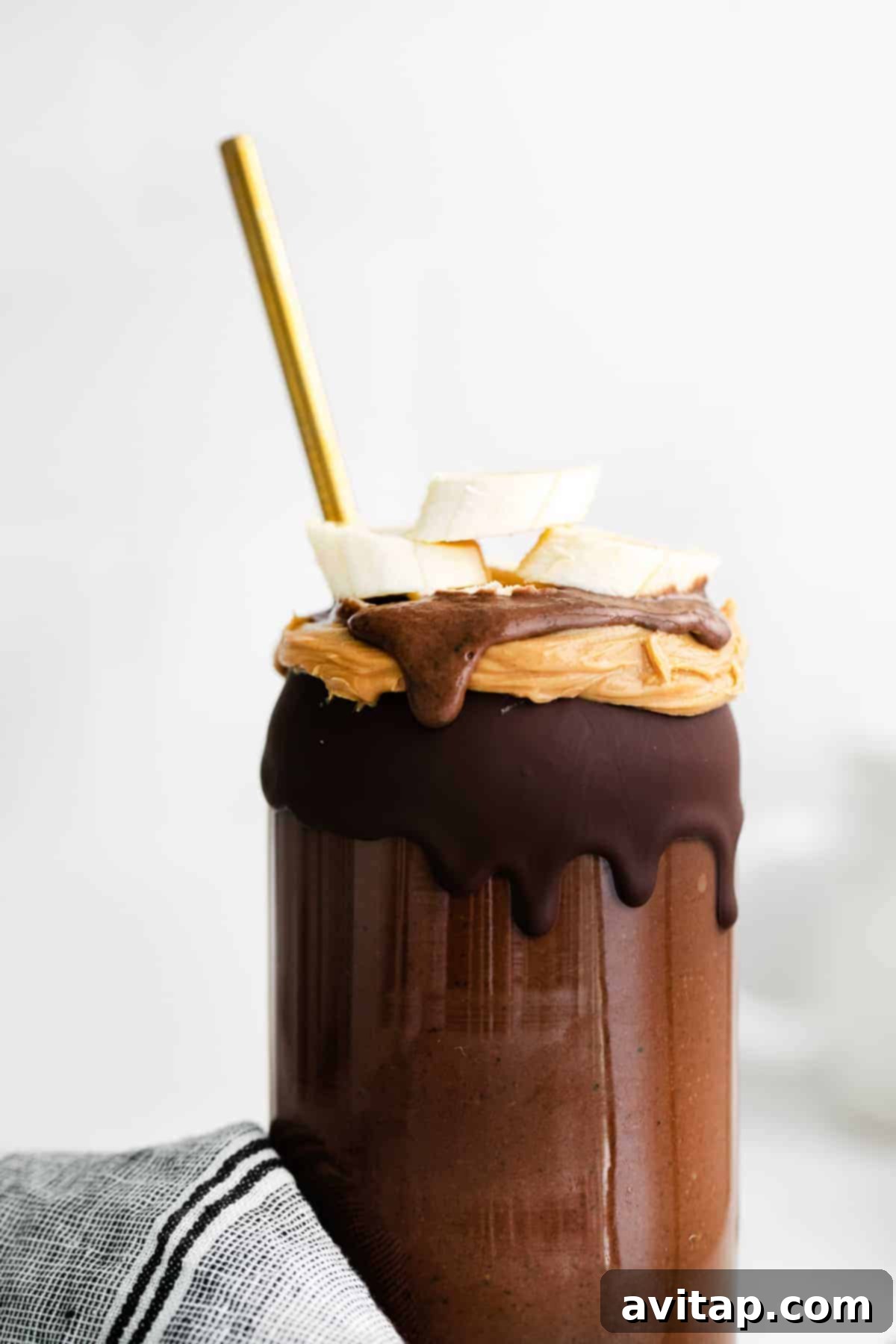 A close-up shot of a smoothie glass rimmed with homemade chocolate magic shell, showing the hardened chocolate texture against the creamy smoothie.