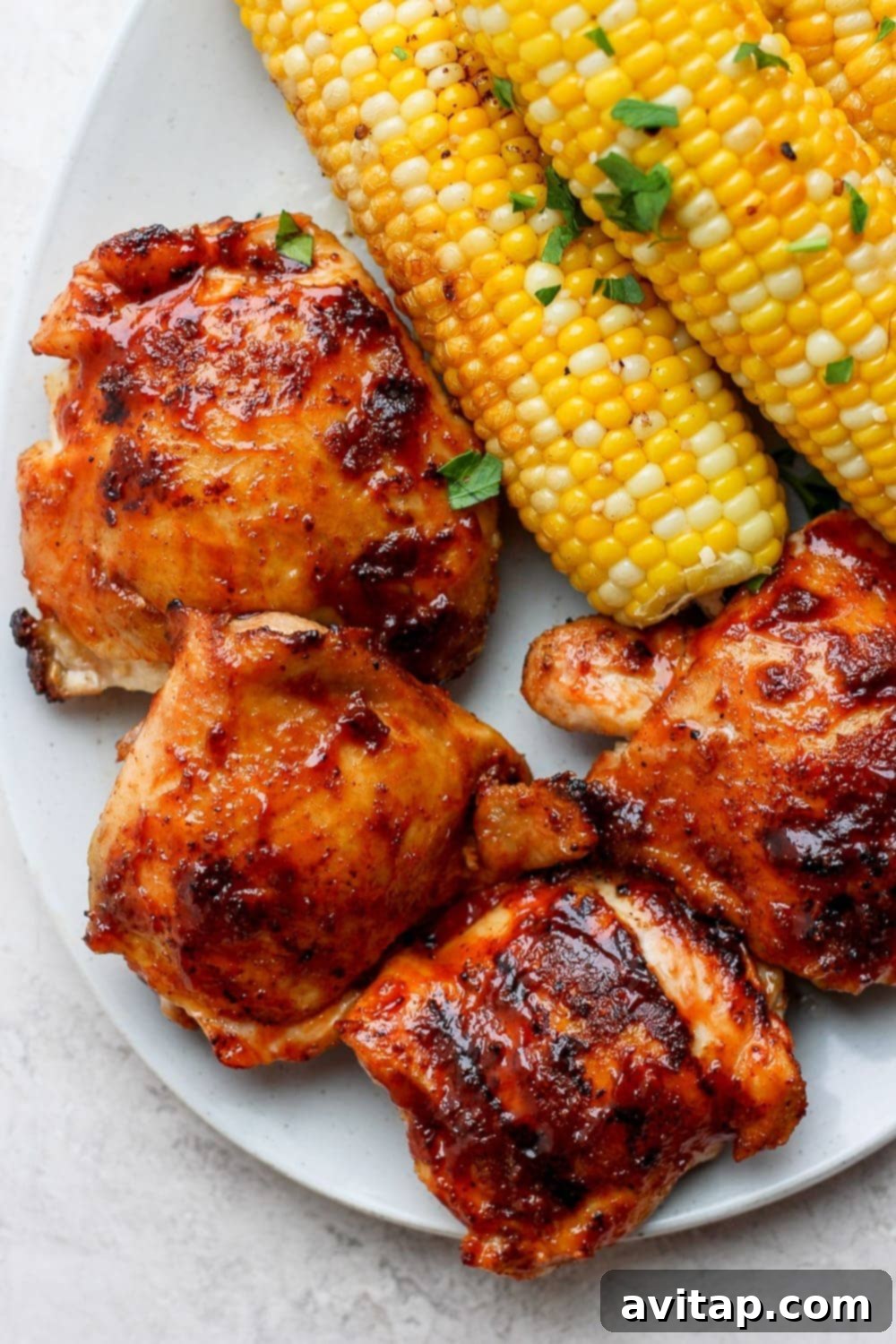 Succulent Grilled Chicken 10 Perfectly grilled chicken thighs on a plate, featuring crispy skin and a tender appearance.