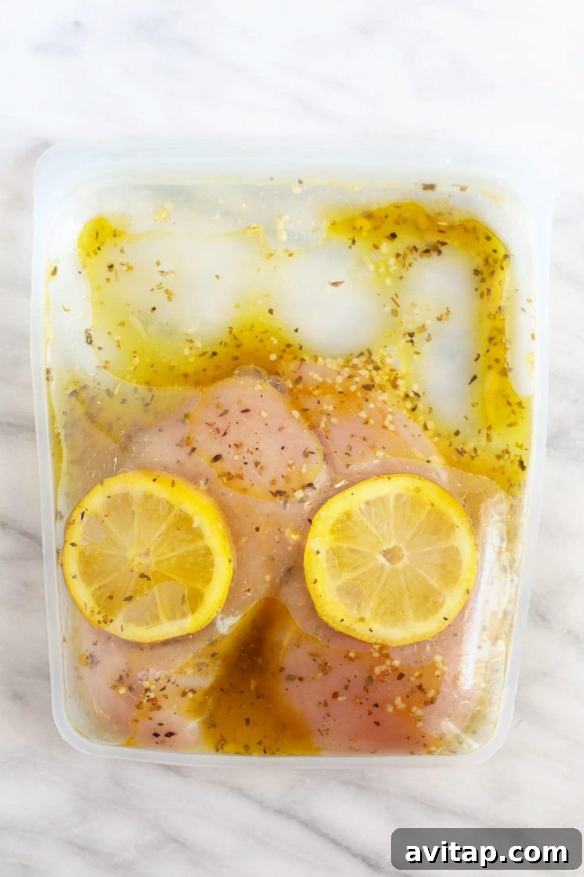 Effortlessly Delicious Greek Chicken Marinade 6 Chicken marinating in a reusable bag with lemon slices and herbs