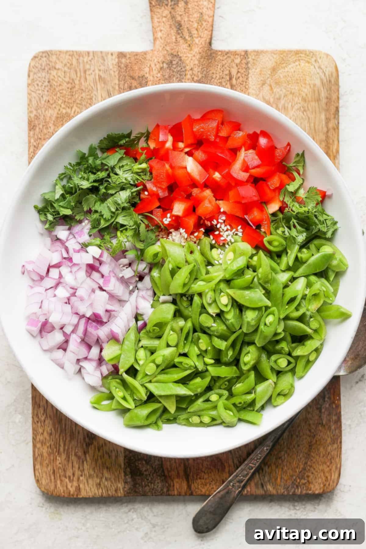 Zesty Ginger Pea Salad 5 Close-up of ginger pea salad ingredients being tossed in a bowl, showing the vibrant colors and fresh textures.