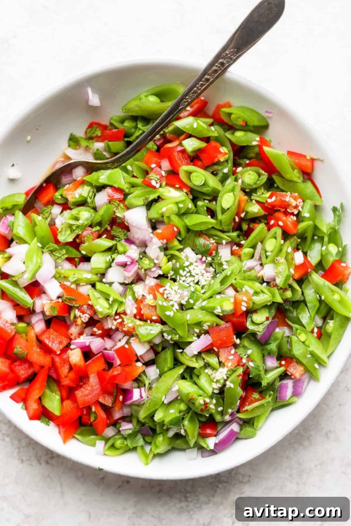 Zesty Ginger Pea Salad 6 A bowl of ginger pea salad, beautifully garnished with sesame seeds, ready to be served.