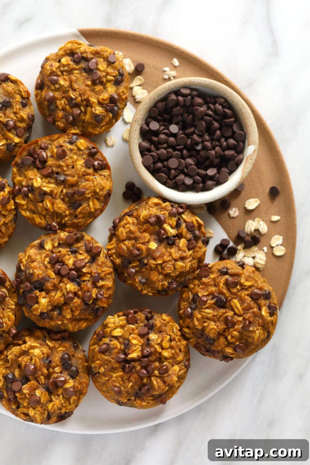 Pumpkin Spice Oatmeal Cups 2 Delicious pumpkin oatmeal cups on a tray with a sprinkle of mini chocolate chips, ready to be enjoyed.