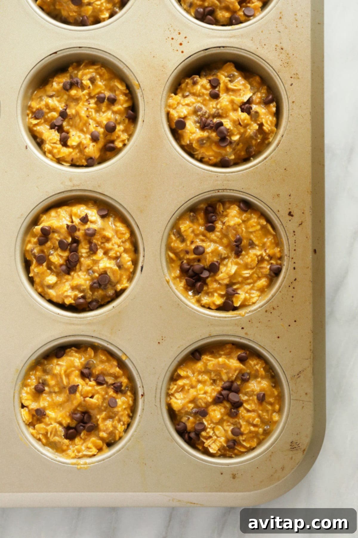 Pumpkin Spice Oatmeal Cups 3 Pumpkin oatmeal cups neatly arranged in a muffin tin, ready to be baked to golden perfection in the oven.