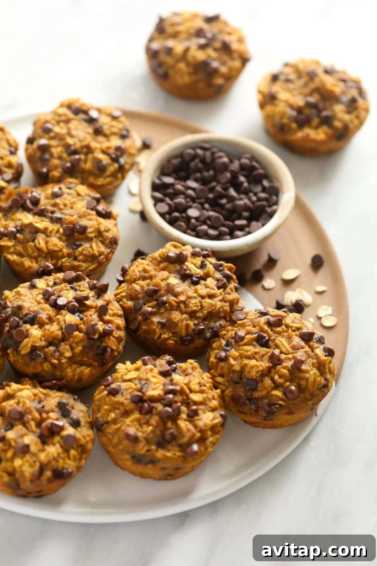 Pumpkin Spice Oatmeal Cups 5 A tray filled with freshly baked pumpkin oatmeal cups, each adorned with mini chocolate chips, ready for serving.