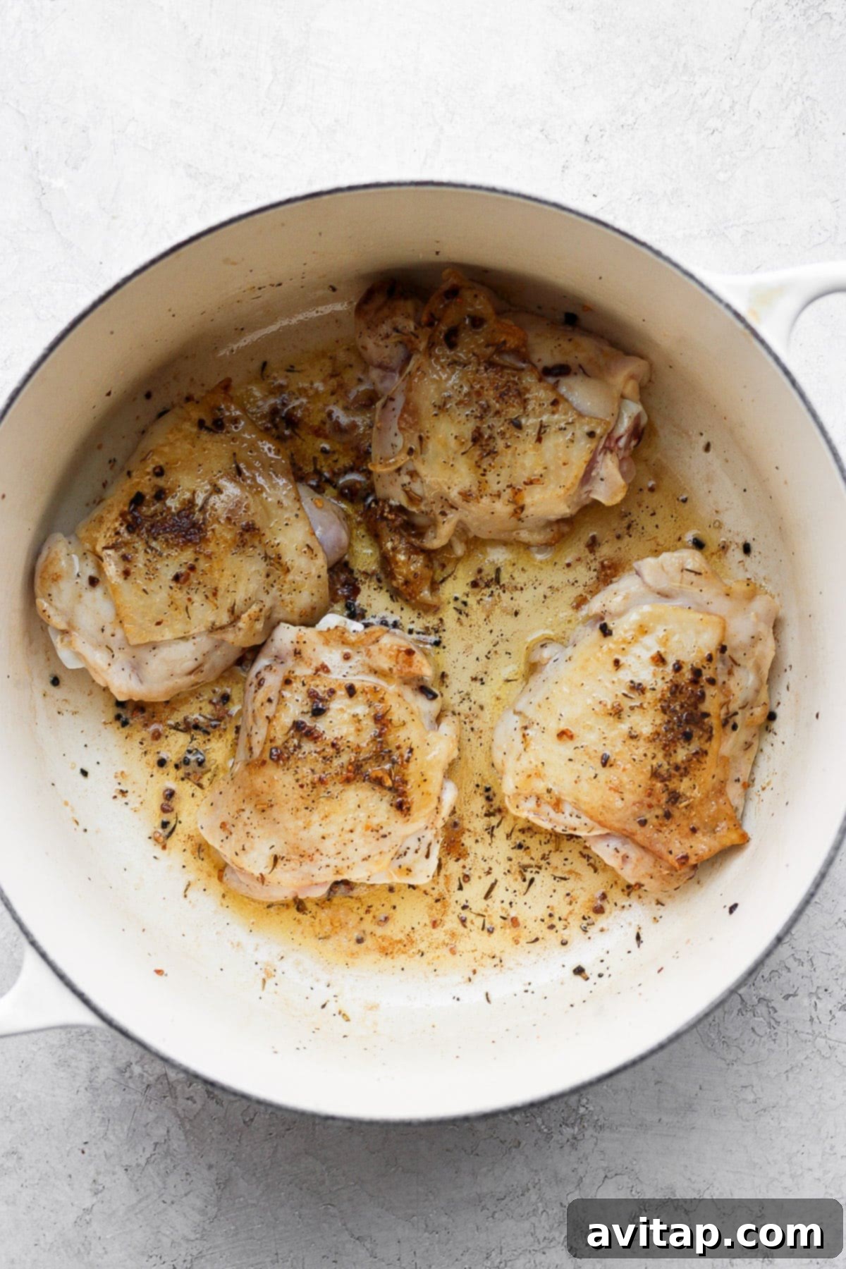 Sautéed chicken thighs browning in a Dutch oven before adding other ingredients, highlighting the start of the cooking process.