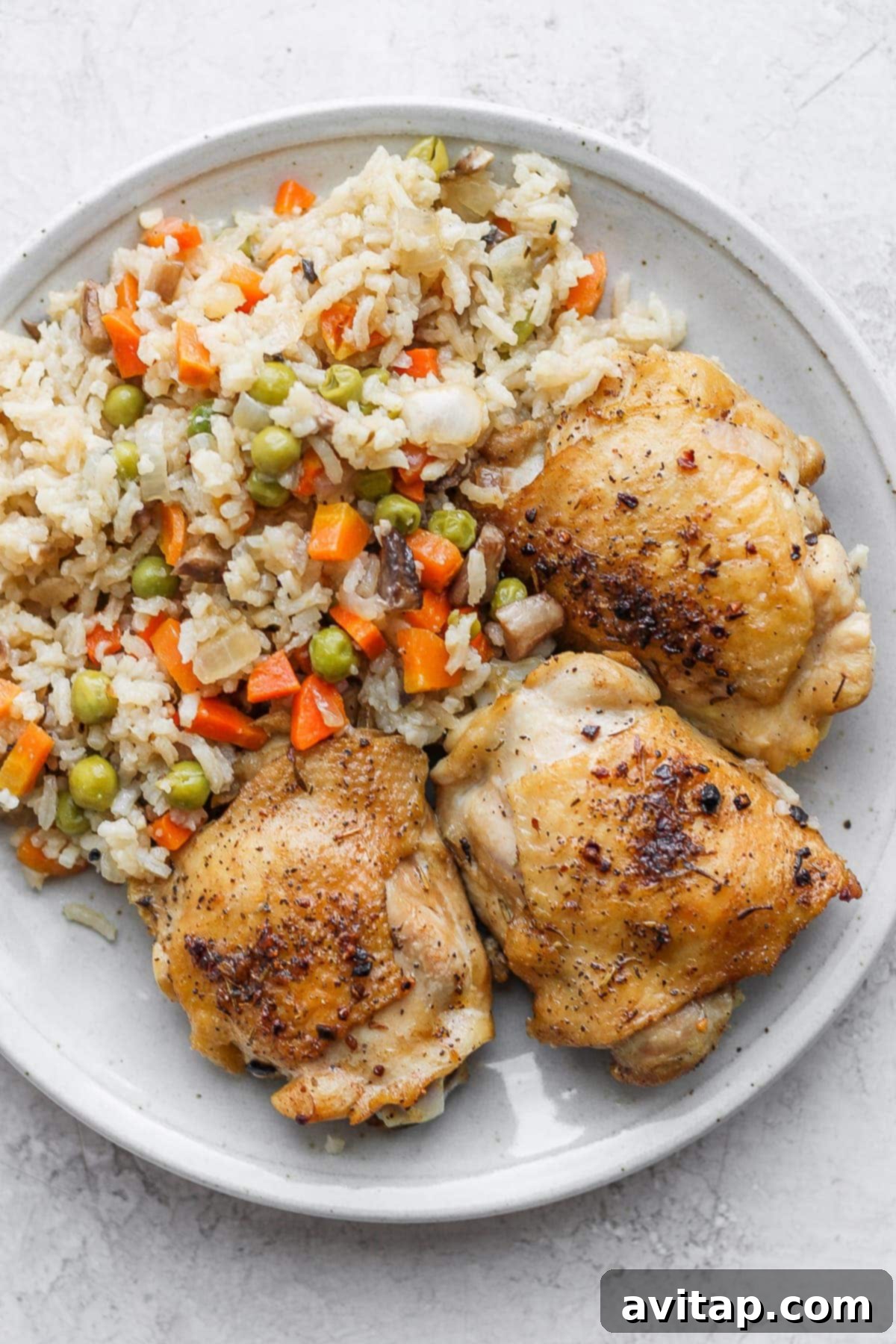 A plated serving of seared chicken thighs and flavorful rice, garnished with fresh parsley, ready to be enjoyed.
