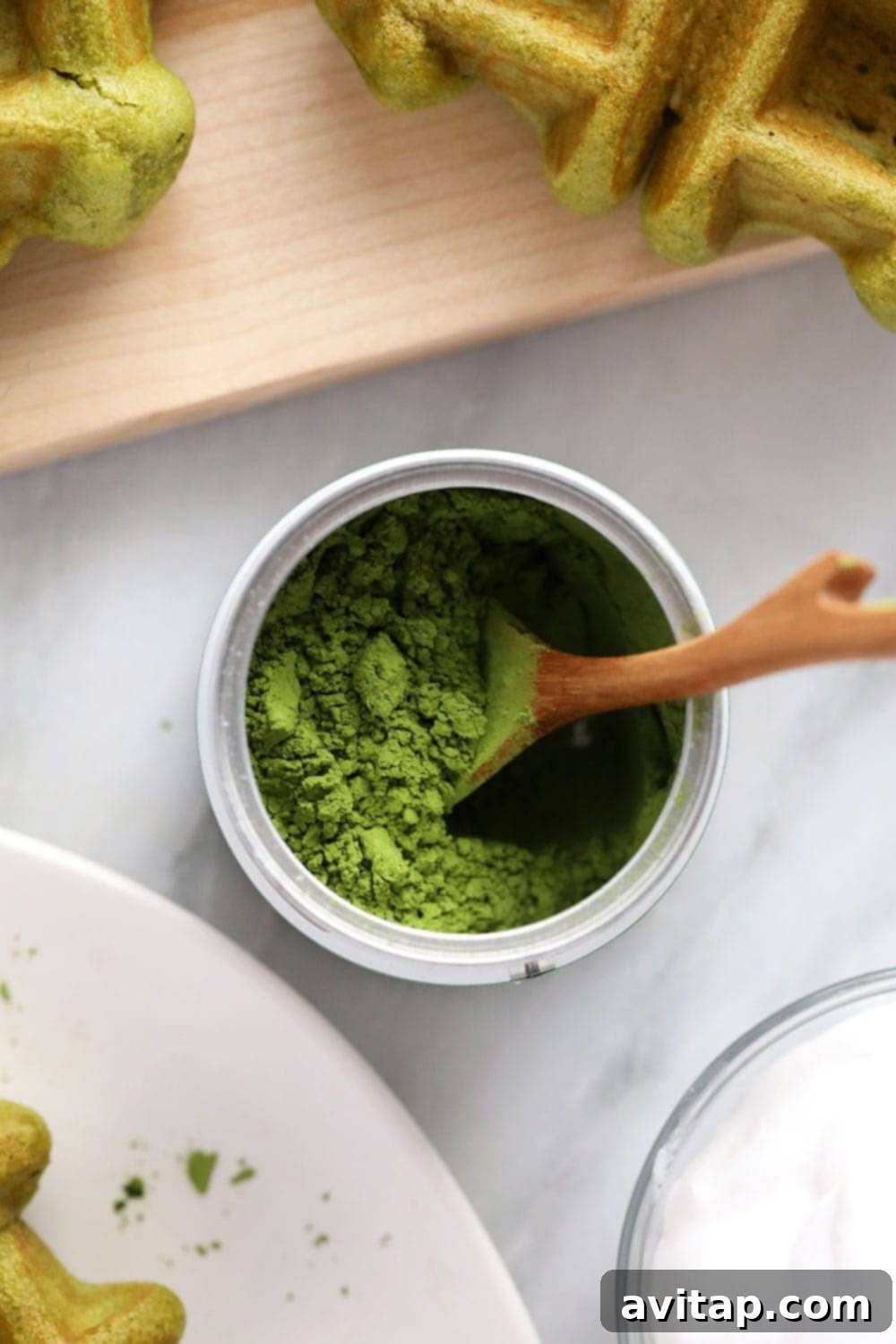 A close-up shot of a can of bright green matcha powder, highlighting its quality.