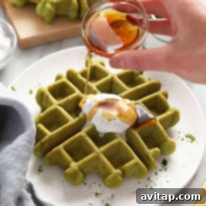 A person is pouring honey on matcha waffles.
