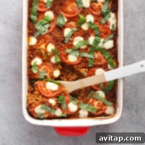 A red baking dish with a tomato and cheese chicken quinoa bake.