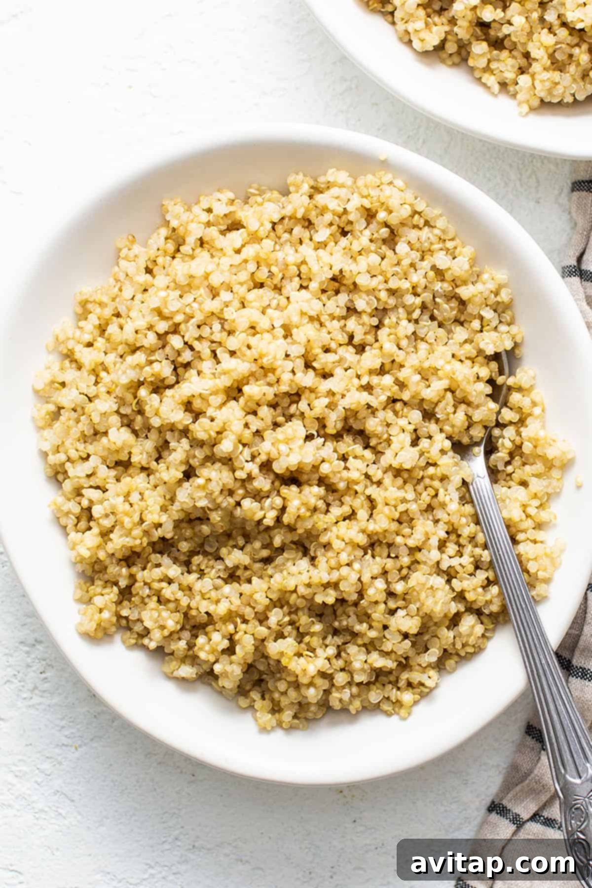 Perfectly cooked, fluffy quinoa in a white bowl with a fork, ready to be enjoyed.