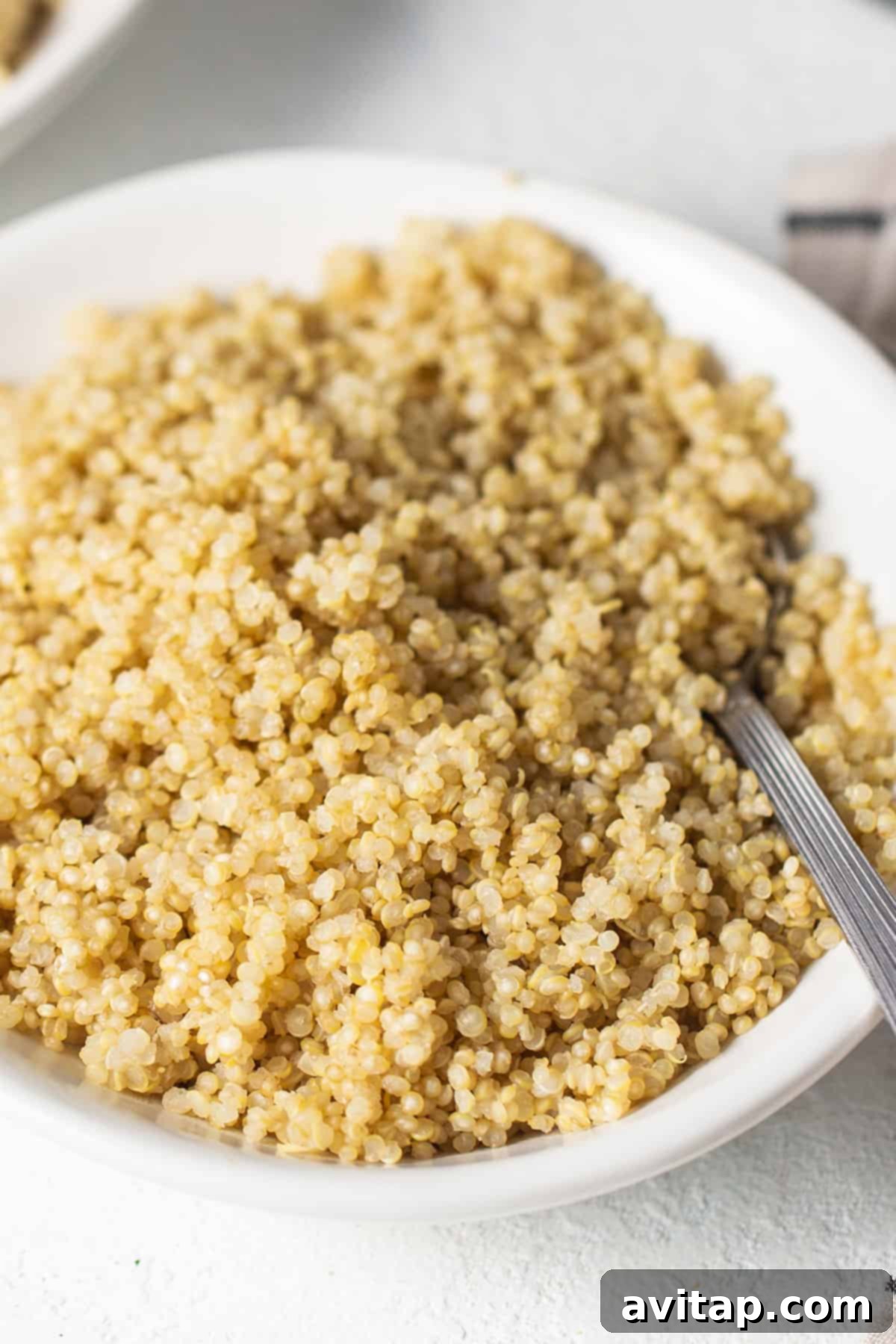 A white bowl filled with perfectly cooked quinoa, prepared using the quick microwave method, ready for a healthy meal.