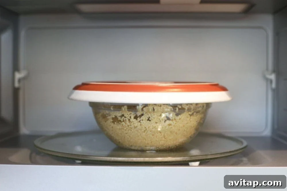 Quinoa in a microwave-safe bowl covered with an inverted plate, placed inside a microwave oven, ready to cook.